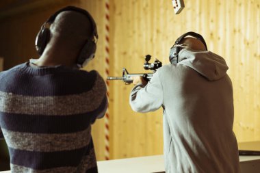 Arkadaşların atış poligonunda tüfeklerle hedefleri vururken eğleniyor. Kapalı alan atış poligonu tesisinde boğa vurarak eğlenen çiftler birbirlerine karşı yarışıyorlar.