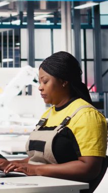 Dikey Video Mühendisi güneş paneli yenilenebilir enerji konfigürasyonlarını gözden geçirir ve güneş pillerinin üretim hattı üzerinde çalışır. Afrika kökenli Amerikalı kadın işçiler CAD endüstriyel yazılımı kullanıyor