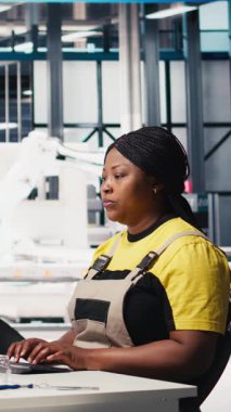 Dikey Video Mühendisi modern fabrikada enerji optimizasyon yazılımı üzerinde çalışan PC üzerindeki güneş paneli sistemlerini yapılandırır. Uzman, yüksek teknolojili, otomatikleştirilmiş bir tesiste fotovoltaik operasyonları yönetiyor.