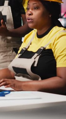 Dikey Video Siyah çalışanları fotovoltaik fabrikasındaki güneş panellerini analiz ediyor, verileri analiz ediyor. Fabrika mühendisleri sorun çözme hataları için belge dosyaları okuyorlar