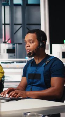 Dikey Video Çağrı Merkezi teknisyeni güneş enerjisi fabrikasındaki bakım soruşturmalarını yürütüyor, müşteri hizmetleri endüstriyel destek bölümünde çalışıyor. Müşterilerle birlikte kulaklık takan Afrikalı Amerikalı bir operatör. Kamera B.