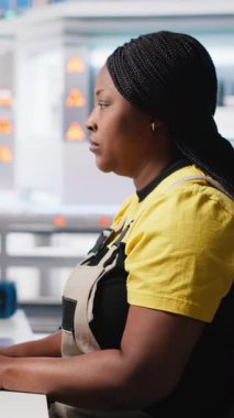 Siyah teknisyenlerden oluşan dikey video ekibi fabrikada üretilen güneş panellerini inceliyor ve üretim hattı için kalite kontrolü yapıyor. Yenilenebilir enerji endüstrisi üzerinde çalışan mühendisler. Kamera A