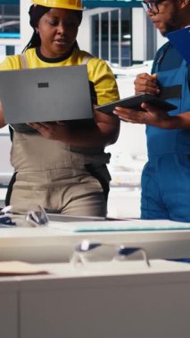 Fotovoltaik fabrikasındaki dikey Video Teknisyenleri grubu cihazlar üzerinde izleme yazılımı kullanıyor, sorunsuz üretim hattı için sorun yaratıyor. Siyah takım, güneş panelleri üreten robotları inceliyor