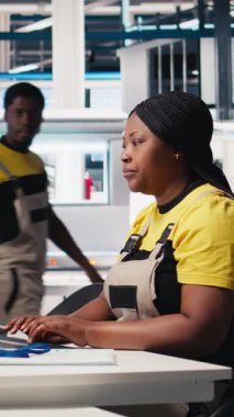 Siyah teknisyenlerden oluşan dikey video ekibi fabrikada üretilen güneş panellerini inceliyor ve üretim hattı için kalite kontrolü yapıyor. Yenilenebilir enerji endüstrisi üzerinde çalışan mühendisler. Kamera B