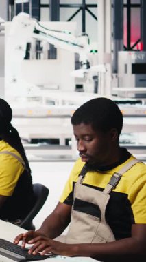 Dikey Video Siyah çalışanı güneş paneli yapılandırmasını masaüstü araçları, fabrika üretimini optimize etme ve sorun giderme yoluyla yönetir. Teknisyen enerji sistemi parametrelerini bilgisayarda güncelliyor. Kamera B.