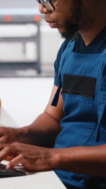 Dikey Video Afrikalı Amerikalı mühendis, bir güneş paneli imalat fabrikasında çalışarak, masaüstündeki güneş enerjisi makinelerinden verileri yönetiyor. Otomatik yenilenebilir enerji üretim hattında erkek teknisyen