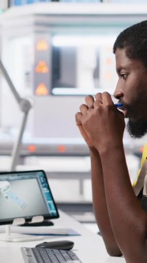 Dikey Video Afrikalı Amerikalı teknisyen, gelişmiş izleme ve üretim araçları kullanarak PC istasyonundaki yenilenebilir enerji ölçümlerini değerlendiriyor. Mühendis güneş enerjisinin hassasiyetini geliştiriyor. Kamera A.