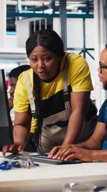 Dikey Video Mühendisleri modern fabrikadaki güneş sistemi yazılımını izliyor, enerji üretimini denetleyen uzmanlardan oluşan bir ekip ve yüksek teknolojili bir fotovoltaik tesisteki ekipmanları yapılandırıyor. Kamera.