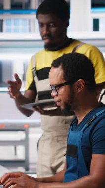 Dikey Video Meslektaşları, sürdürülebilir bir endüstriyel fabrikadaki bilgisayar istasyonundan güneş enerjisi teçhizatı çekiyorlar. Siyah mühendislik ekibi CAD yazılım ayarlamalarıyla ilgileniyor. Kamera.