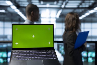Bulanık arkaplandaki mühendislerin önündeki ağ sanallaştırması yapan izole ekran laptopuna odaklan. Sunucu çiftliğindeki yöneticiler tarafından kullanılan model kroma anahtar defterini kapat ve ayarları doğrula