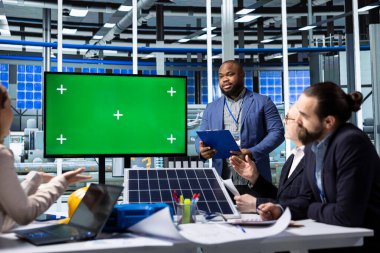 Güneş panellerini gösteren modelleme ekranını kullanan işadamları araştırma veri analizi tasarlıyor. Ofisteki yenilikçi fotovoltaik materyalleri araştıran yeşil ekran monitörüne bakan fabrika uzmanları