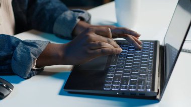 Evden çalışan bir tele-işçi, dizüstü bilgisayarda klavye kullanıyor, belge yazıyor. Uzaktan çalışan klavyedeki tuşlara basıyor, iş ortaklarına e-posta gönderiyor, kamera A yakın plan