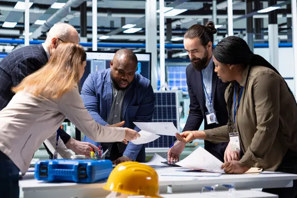 Endüstriyel fabrika hissedarları potansiyel yatırım fırsatları üzerine araştırma yapıyorlar, evrak okuyorlar. Fabrika hissedarları rekabet analizi yapıyor, eğilimleri belirliyor, dosyalara bakıyor