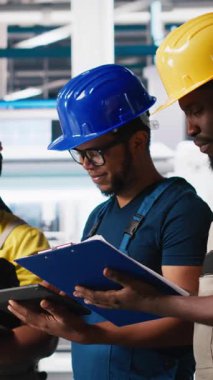 Dikey Video Güneş Panelleri Mühendisleri ekibi üretim tesisinde bulunan cihazları kullanarak yeni fotovoltaik materyaller geliştiriyor. Siyahi işçi grubu daha iyi üretim bandı için deneyler yapıyor. Kamera.