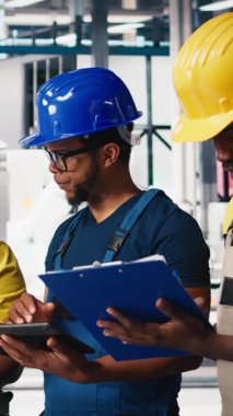 Güneş paneli fabrikasındaki dikey Video Mühendisliği grubu tablet aracılığıyla makine ayarlarını ayarlıyor, verimli üretim için üretim ve yapılandırmayı denetliyor. Takım çalışması. Kamera B.