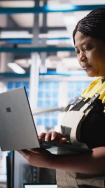 Dikey Video Photovoltaics fabrikası teknisyeni dizüstü bilgisayarda CAD modelleri ve güneş modülleri için teknik çizimler tasarlıyor. Kadın mühendis, verimlilik ve üretim için güneş paneli tasarımlarını güvence altına alıyor