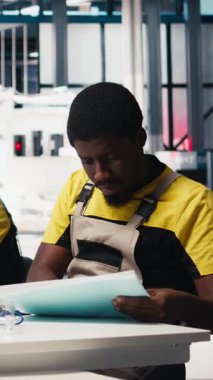 Dikey Video Afrikalı Amerikalı denetleyici, güneş enerjisi üretim teknolojisiyle çevrili ofis bilgisayarındaki enerji kontrol sistemlerini inceliyor. Erkek mühendis güneş enerjisi ve üretimi dengeler. Kamera B.