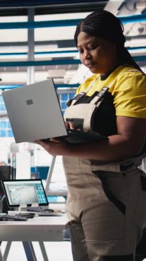 Dikey Video Photovoltaics fabrikası teknisyeni dizüstü bilgisayarda CAD modelleri ve güneş modülleri için teknik çizimler tasarlıyor. Kadın mühendis, verimlilik ve üretim için güneş paneli tasarımlarını güvence altına alıyor