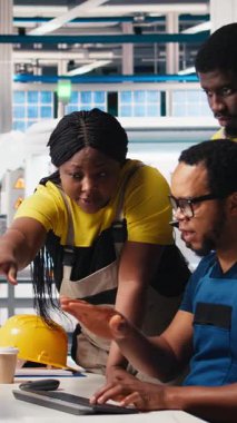 Dikey Video Photovoltaics tesis çalışanları, güneş panellerini montaj hatlarına yerleştiren robot kollarının performansını değerlendiriyor. Tüm siyah takımlar üretim sürecine bilgisayarda, güneş santralinde bakıyorlar.