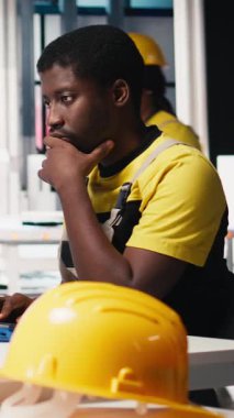 Dikey Video Uzmanı, yüksek teknoloji üretim tesisinde çalışan güneş paneli üretimi için makine parametrelerini ayarlar. Siyah mühendis bilgisayarda teknik verileri analiz ediyor. Kamera B.