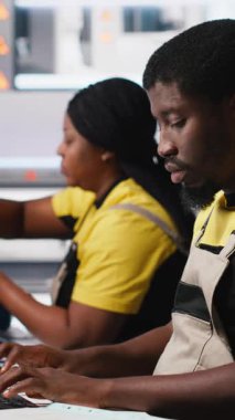 Dikey Video Siyah çalışanı güneş paneli yapılandırmasını masaüstü araçları, fabrika üretimini optimize etme ve sorun giderme yoluyla yönetir. Teknisyen enerji sistemi parametrelerini bilgisayarda güncelliyor. Kamera A.