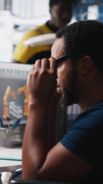 Dikey Afrikalı Amerikan tekerlekli sandalye kullanıcısı güneş paneli fabrikasında çalışarak yenilenebilir enerji sistemlerini optimize ediyor. Mühendis, engelli dostu bir enerji santralinde robot silah otomasyonunu inceliyor.