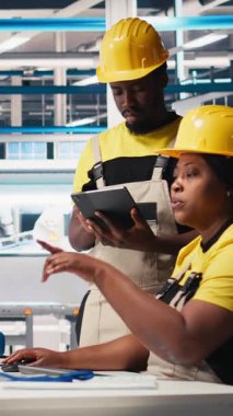 Dikey Video Siyah çalışanları fotovoltaik fabrikasındaki güneş panellerini analiz ediyor, verileri analiz ediyor. Fabrika mühendisleri sorun çözme hataları için belge dosyaları okuyorlar