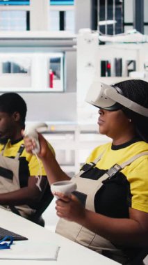 Dik Video Photovoltaics fabrika teknisyeni dijital güneş pillerini monte etmek için VR kulaklık kullanıyor, güneş panellerini robot kolları aracılığıyla yerleştiriyor. Sanal kullanarak güneş santrali makinelerini denetleyen kadın uzman