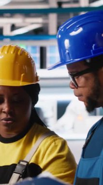 Güneş paneli fabrikasındaki dikey Video Mühendisliği grubu tablet aracılığıyla makine ayarlarını ayarlıyor, verimli üretim için üretim ve yapılandırmayı denetliyor. Takım çalışması. Kamera A.