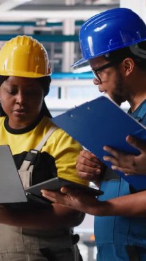 Fotovoltaik fabrikasındaki dikey Video Teknisyenleri grubu cihazlar üzerinde izleme yazılımı kullanıyor, sorunsuz üretim hattı için sorun yaratıyor. Siyah takım, güneş panelleri üreten robotları inceliyor