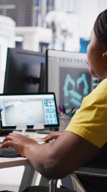 Dikey Görüntü Photovoltaics fabrikası çalışanı güneş paneli üretiminin performansını izlemek için PC kullanıyor. Mühendis maluliyet dostu endüstriyel tesiste çalışıyor. Kamera A.