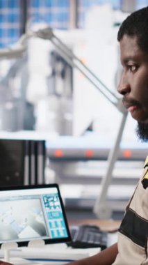 Vertical Video PC tabanlı solar teknisyen üretim fabrikasındaki otomasyon verilerini gözden geçiriyor, üretim endüstrisi yenilenebilir enerjiye odaklanıyor. İşçi güneş panellerini ve makine performansını izliyor. Kamera A