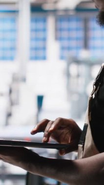 Güneş paneli tesisindeki dikey video teknisyeni fotovoltaik sistem performansını dizüstü bilgisayardan inceliyor. Endüstriyel santralde verimliliği optimize etmek için üretim çizgisi ölçümlerini analiz eden uzman