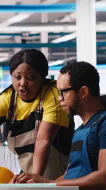 Dikey Video Photovoltaics fabrika ekibi güneş panelleri elle üretimini inceleyerek bilgisayar programındaki performansını izliyor. Siyahi çalışanlardan oluşan bir grup fabrika mekanizması parametrelerini okuyor. Kamera A.