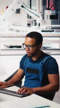 Dikey Video Afrikalı Amerikalı mühendis, bir güneş paneli imalat fabrikasında çalışarak, masaüstündeki güneş enerjisi makinelerinden verileri yönetiyor. Otomatik yenilenebilir enerji üretim hattında erkek teknisyen