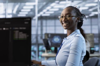 Sunucu odası sıralarını kontrol etmekle görevli neşeli bir kadının portresi farklı iş yükleri için bilgisayar kaynakları sağlıyor. PC kullanarak veri merkezi ana bilgisayarlarını araştıran neşeli yönetici