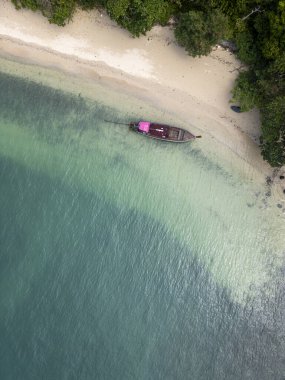 Tayland koyunda yelkenli tekneleri olan tropikal bir adanın havadan görünüşü sakin bir gölde sürüklenen yelkenli teknelerinin olduğu çarpıcı bir seyahat rotası. Palmiye ağaçları, altın plajlar ve turkuaz bir okyanus..
