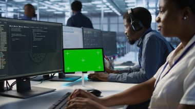 Sistem yöneticileri tarafından en az arayı sağlamak için kullanılan sunucu odasındaki yeşil tableti kapat. Veri merkezi yazılım geliştiricileri krom anahtar cihazına bakıyor, performansı izliyor, kamera A