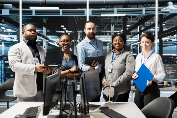 Gülümseyen veri merkezi teknisyeninin portresi. Denetleme ekipmanları, bakım işleri. Mutlu sunucu çiftliği ekip çalışanları platformlar arasında işlevsel dengeyi sağlamak için sistem kontrolleri yapıyor