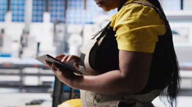 Güneş paneli üreten bitki araştırmacısı tablet üzerine notlar alıyor, yeni güneş enerjisi sistemleri prototipleri geliştiriyor. Mühendis yeni fotovoltaik materyalleri inceliyor, bilgi yazıyor. Kamera A.