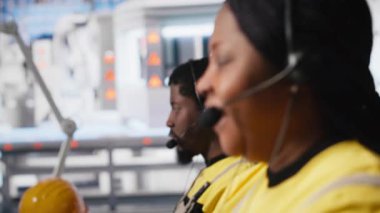 Fotovoltaik tesisteki yardım masasında çalışan siyah mühendis, kulaklıkla çağrılara cevap veriyor, teknik sorunları çözmede yardım ve destek öneriyor. Kadın operatör yardım hattında. Kamera A.