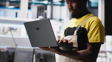 Güneş paneli fabrikasındaki erkek mühendis fotovoltaik sistem performansını dizüstü bilgisayardan inceliyor. Verimliliği ve sorun çıkarmayı optimize etmek için dizüstü bilgisayardaki üretim hattını analiz ediyorum. Kamera A.