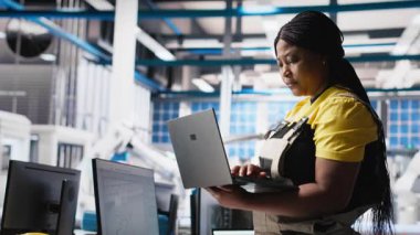 Fotovoltaik fabrikası teknisyeni dizüstü bilgisayarda CAD modelleri ve güneş modülleri için teknik çizimler tasarlıyor. Kadın mühendis, verimlilik ve üretim için güneş paneli tasarımlarını güvence altına alıyor. Kamera A.