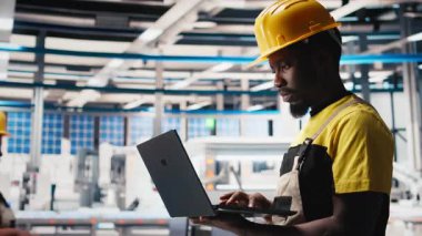 Güneş paneli fabrikasındaki erkek mühendis fotovoltaik sistem performansını dizüstü bilgisayardan inceliyor. Verimliliği ve sorun çıkarmayı optimize etmek için dizüstü bilgisayardaki üretim hattını analiz ediyorum. Kamera B.