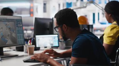 Güneş panelleri üretmek için CAD yazılımını test eden Afro-Amerikan tekerlekli sandalye kullanıcısı, güneş enerjisi endüstrisinde çalışan fabrika mühendisi. İşinde engelli bir uzman. Kamera A.