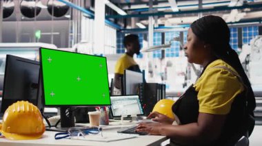 Fotovoltaik fabrikasında çalışan siyah bir kadın güneş panelleri montaj süreçlerini geliştirmek için bilgisayar üzerindeki fotokopi alanını kullanıyor. Ekipmanları kalibre etmek için bilgisayar kullanarak montaj hattı mühendisi. Kamera B.