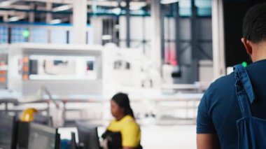 Siyah teknisyen, güneş paneli montaj hattını masaüstü bilgisayarından üreten fabrikanın üretim hattını optimize ediyor. Erkek mühendis alternatif enerji üzerinde çalışıyor. Kamera B.