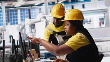 Afrika kökenli Amerikalı işçiler güneş paneli fabrikasındaki imalat ekipmanlarını kontrol ediyor, belge dosyalarını okuyor. Endüstriyel tesisteki mühendisler üretim sürecini inceliyor. Kamera A.