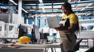 Fotovoltaik fabrikası teknisyeni dizüstü bilgisayarda CAD modelleri ve güneş modülleri için teknik çizimler tasarlıyor. Kadın mühendis, verimlilik ve üretim için güneş paneli tasarımlarını güvence altına alıyor. Kamera B.