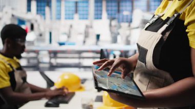 Fotovoltaik fabrikası çalışanı tablet üzerindeki güneş modülleri için CAD teknik çizimleri inceleyerek montaj sürecini inceliyor. Güneş paneli tasarımlarını geliştiren bir teknisyen. Kamera B.